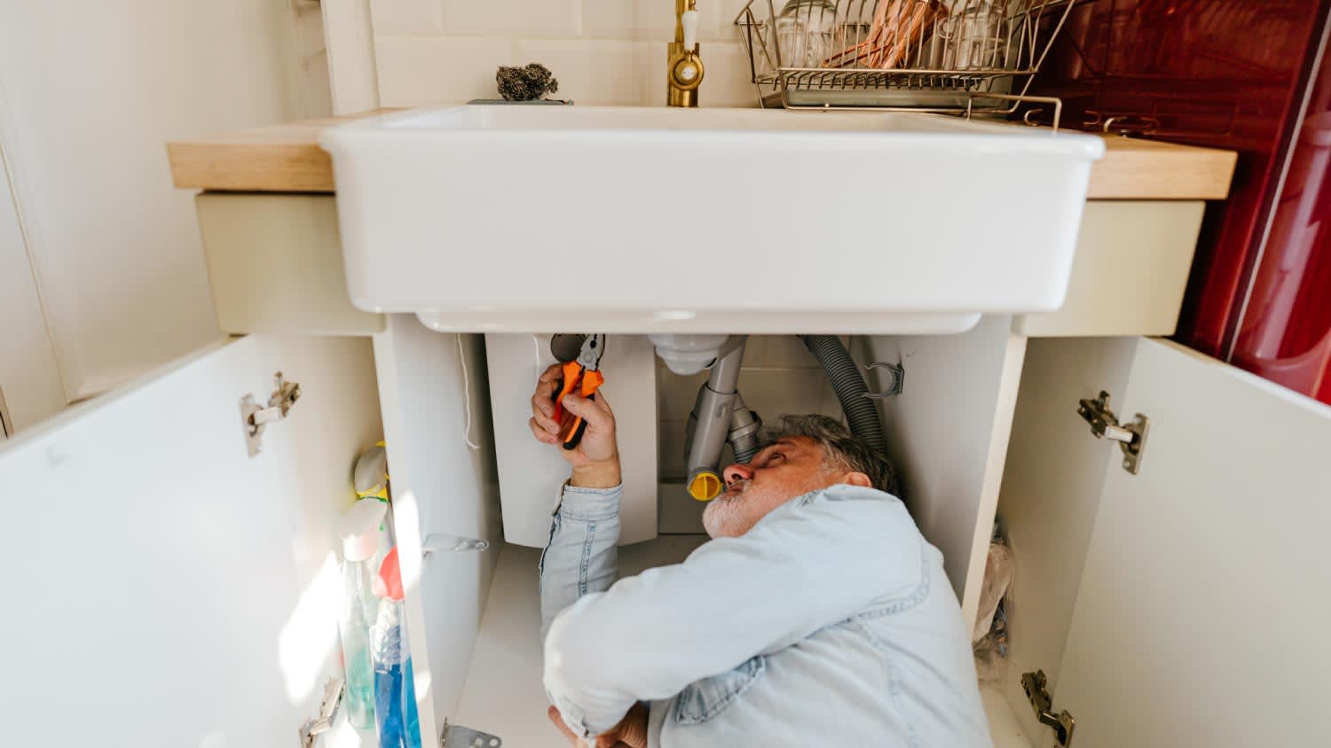 A man solving plumbing problems in a kitchen