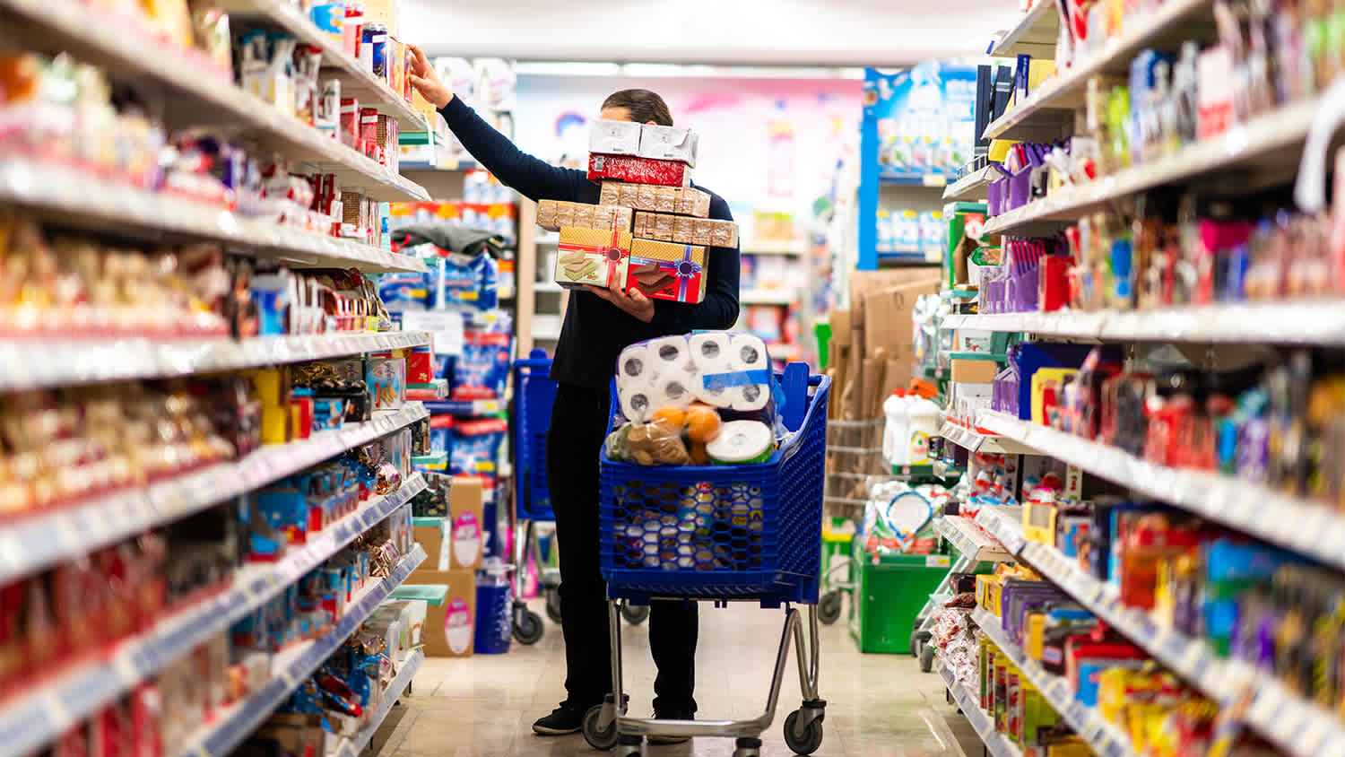man in supermarket overfilling cart