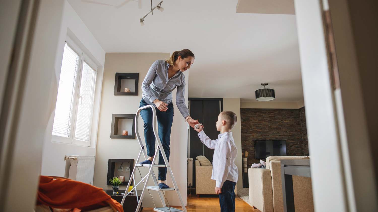 A woman learning to her child changing a light bulb