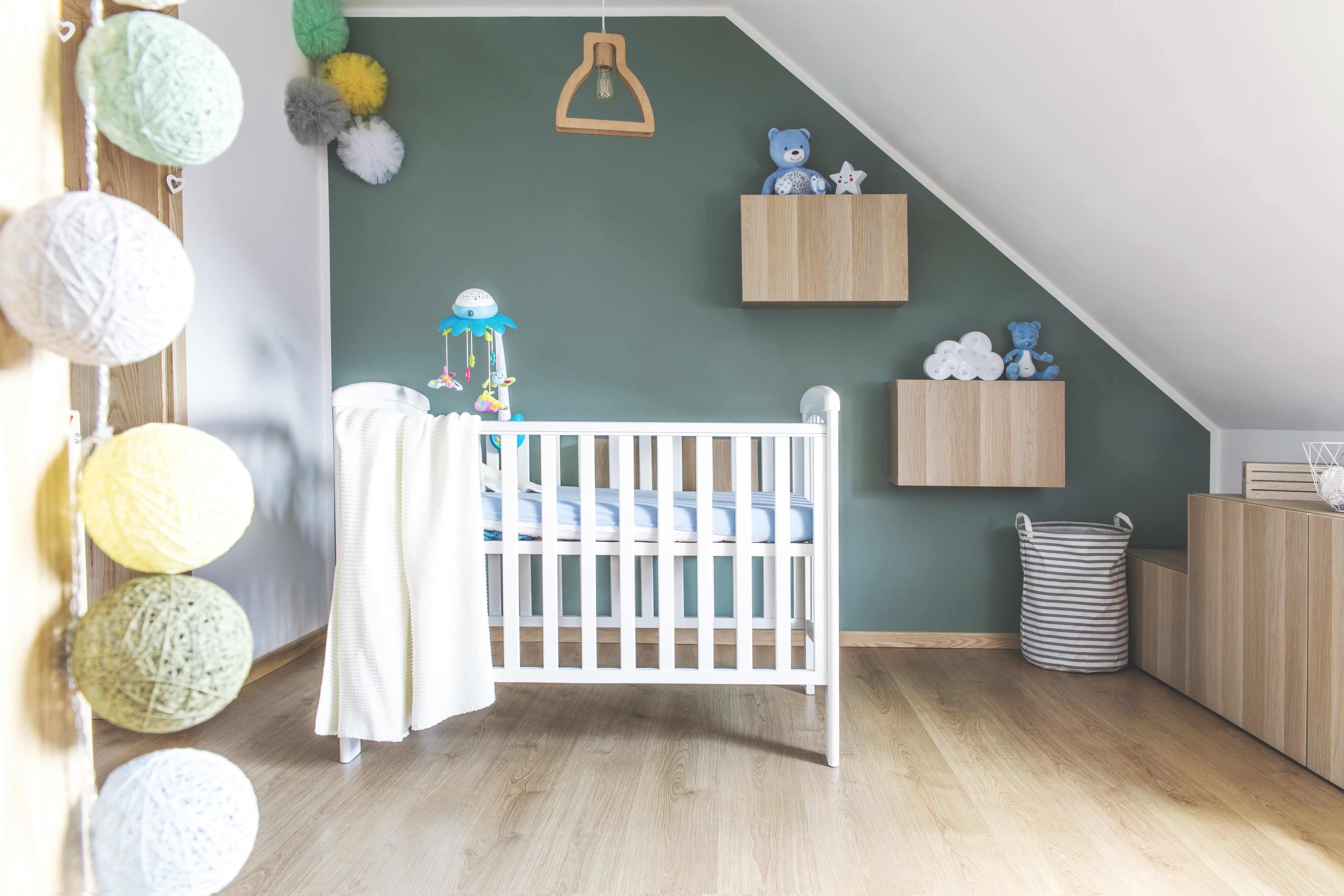Nursery with hunter green accent wall, teddy bears, wall poufs, and cotton ball string lights