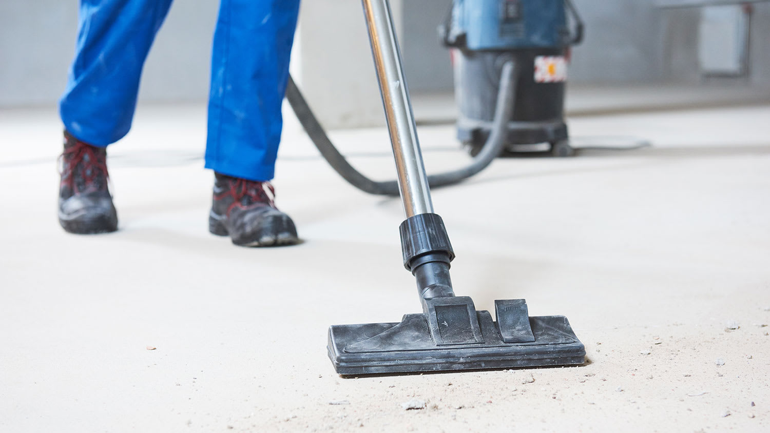 worker using shop vacuum to remove dust