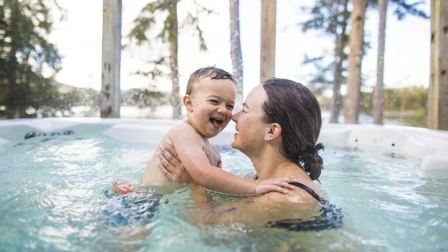 Boy playing with his mother in hot tub