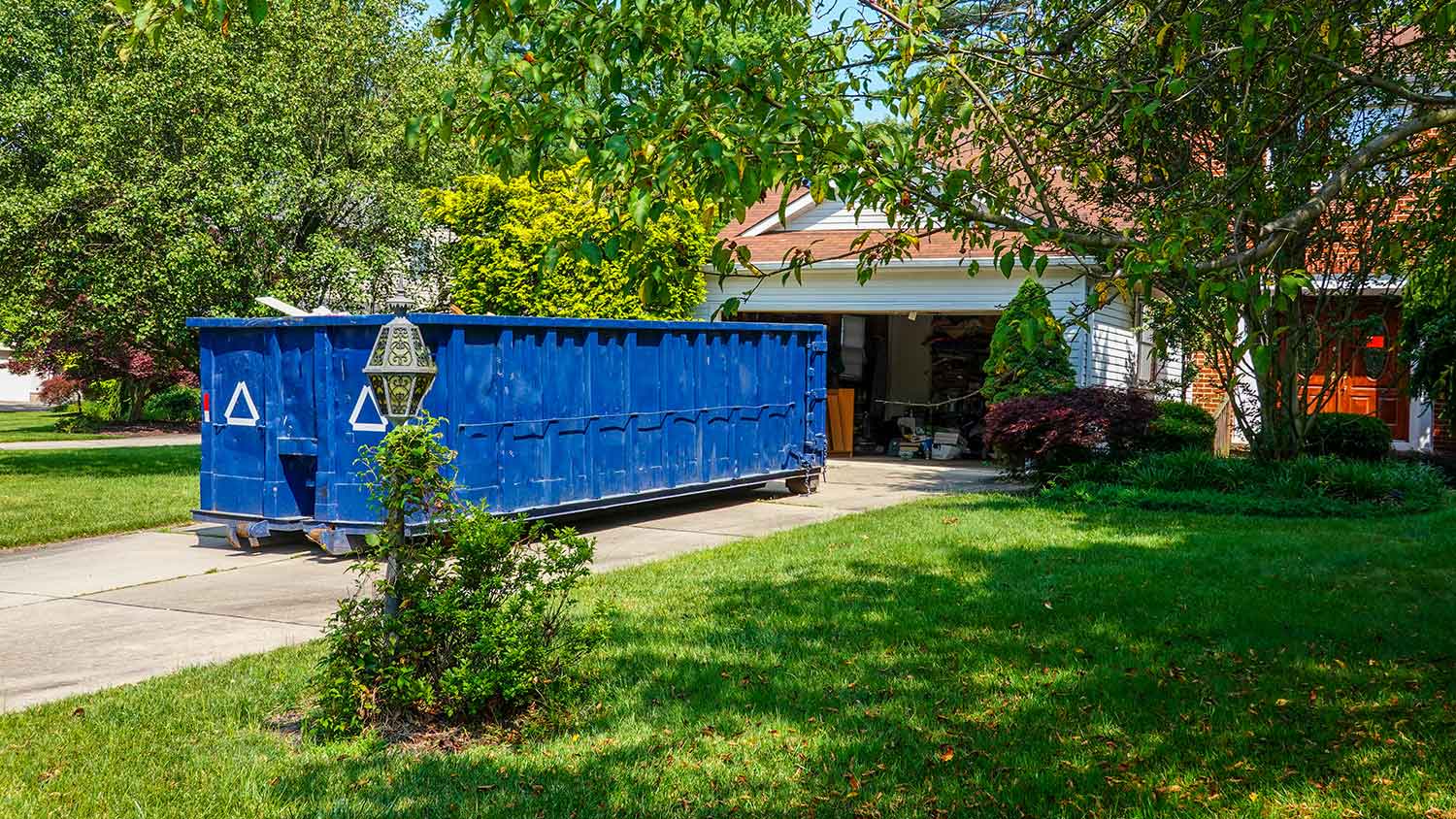 Blue construction dumpster in a house driveway