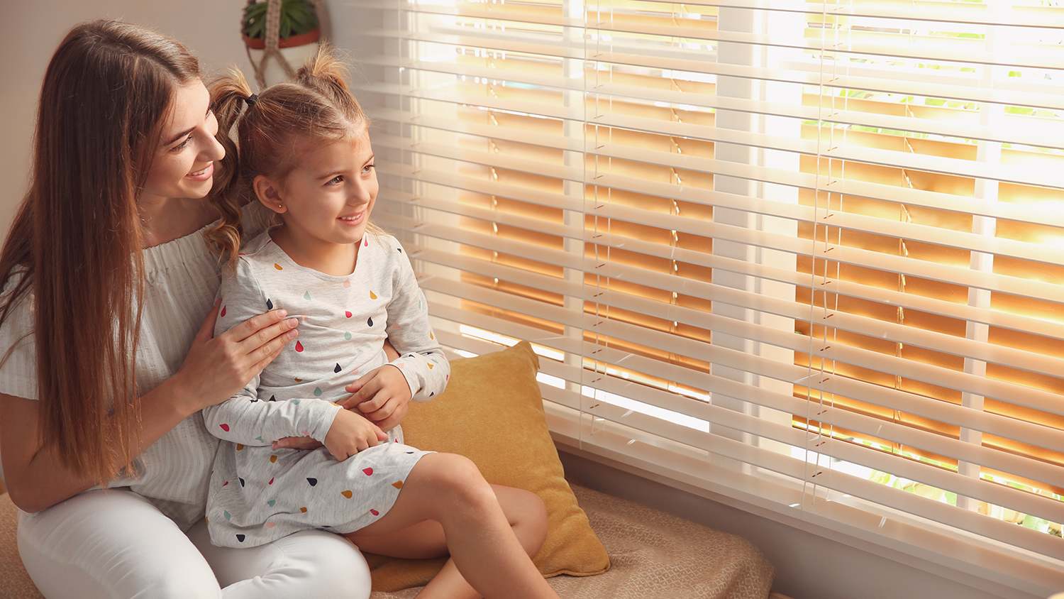 woman cozy at home with daughter looking out the window