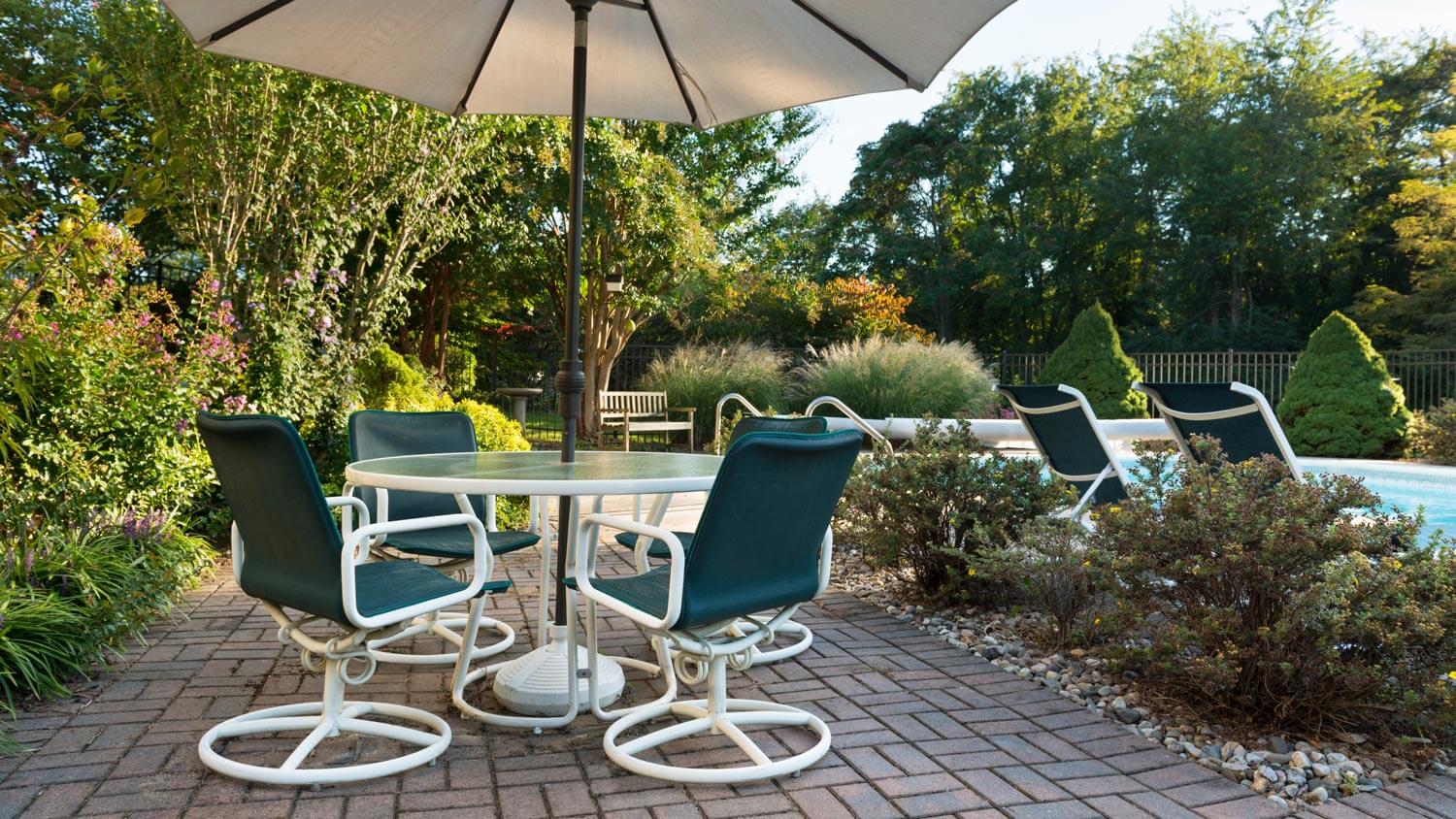 A backyard with a patio and pool with pavers