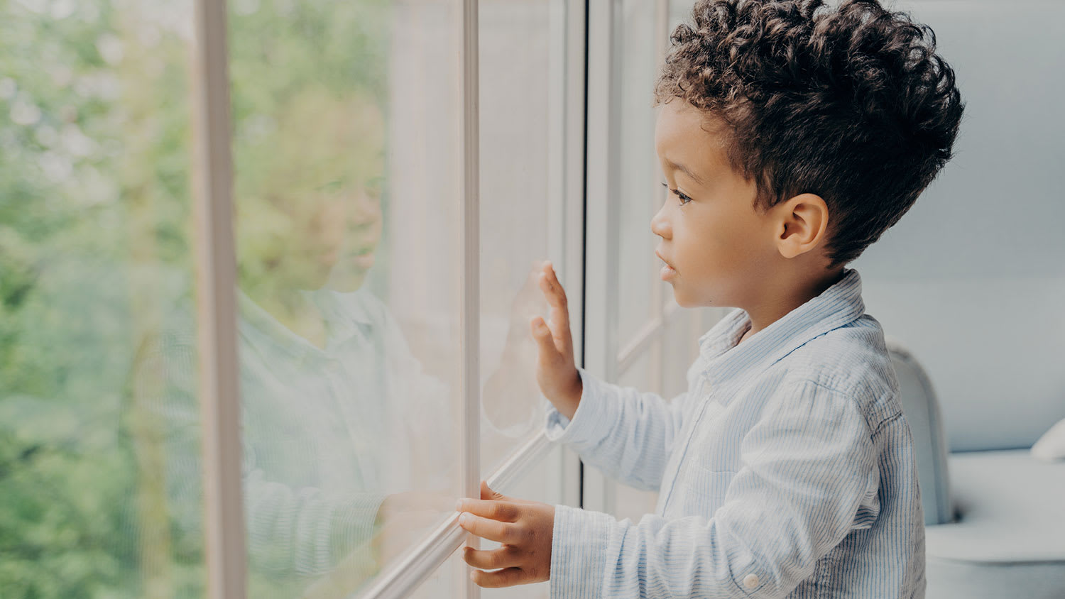 Little boy looking out a big window