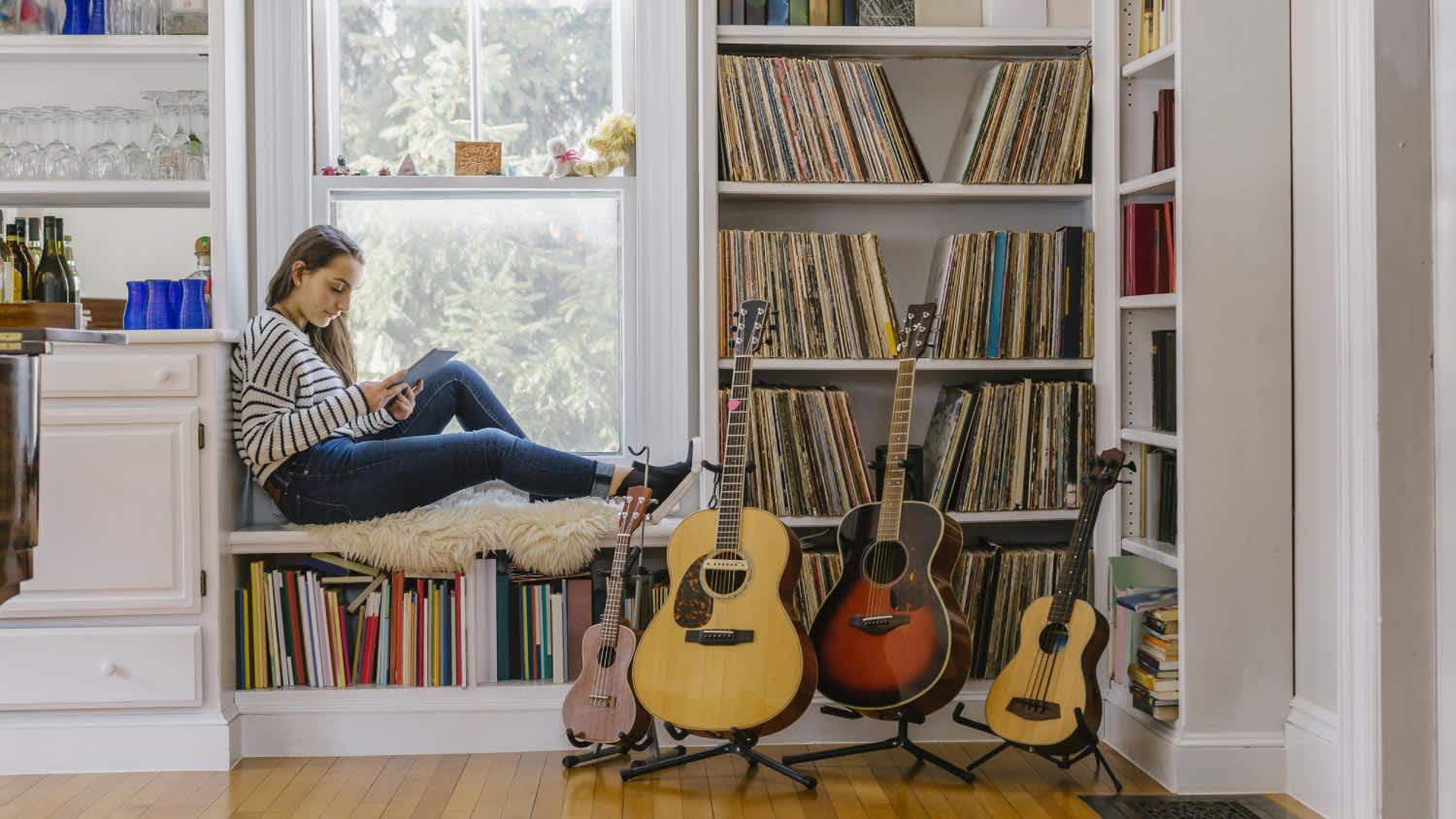 Teenager seated in window working on tablet