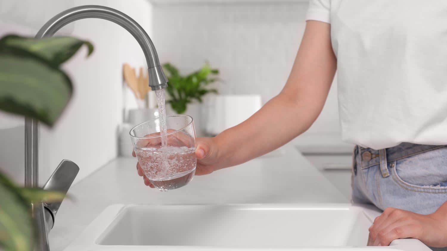 A woman filling a glass of water from the tap
