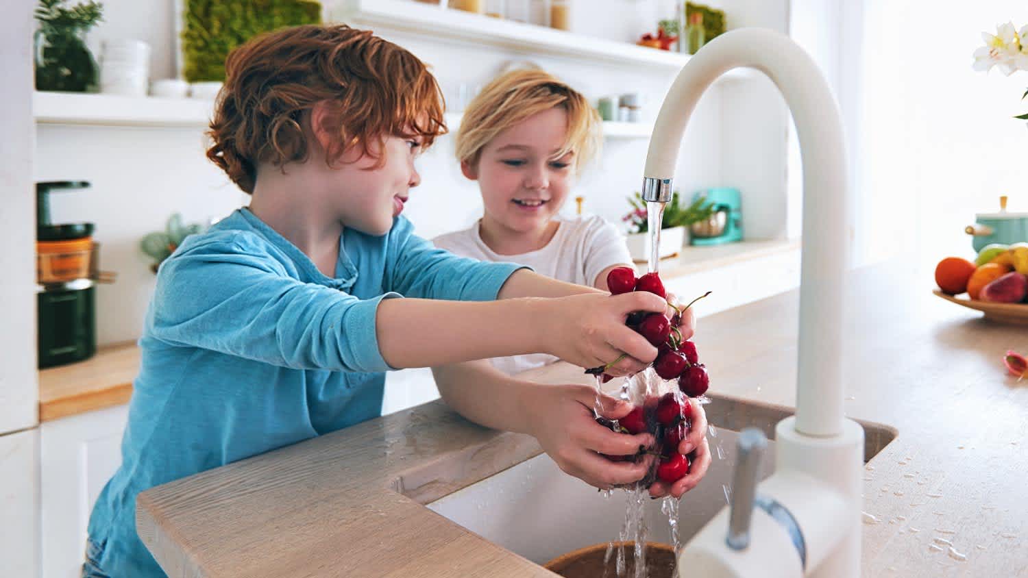 Kids washing cherries under the tap water