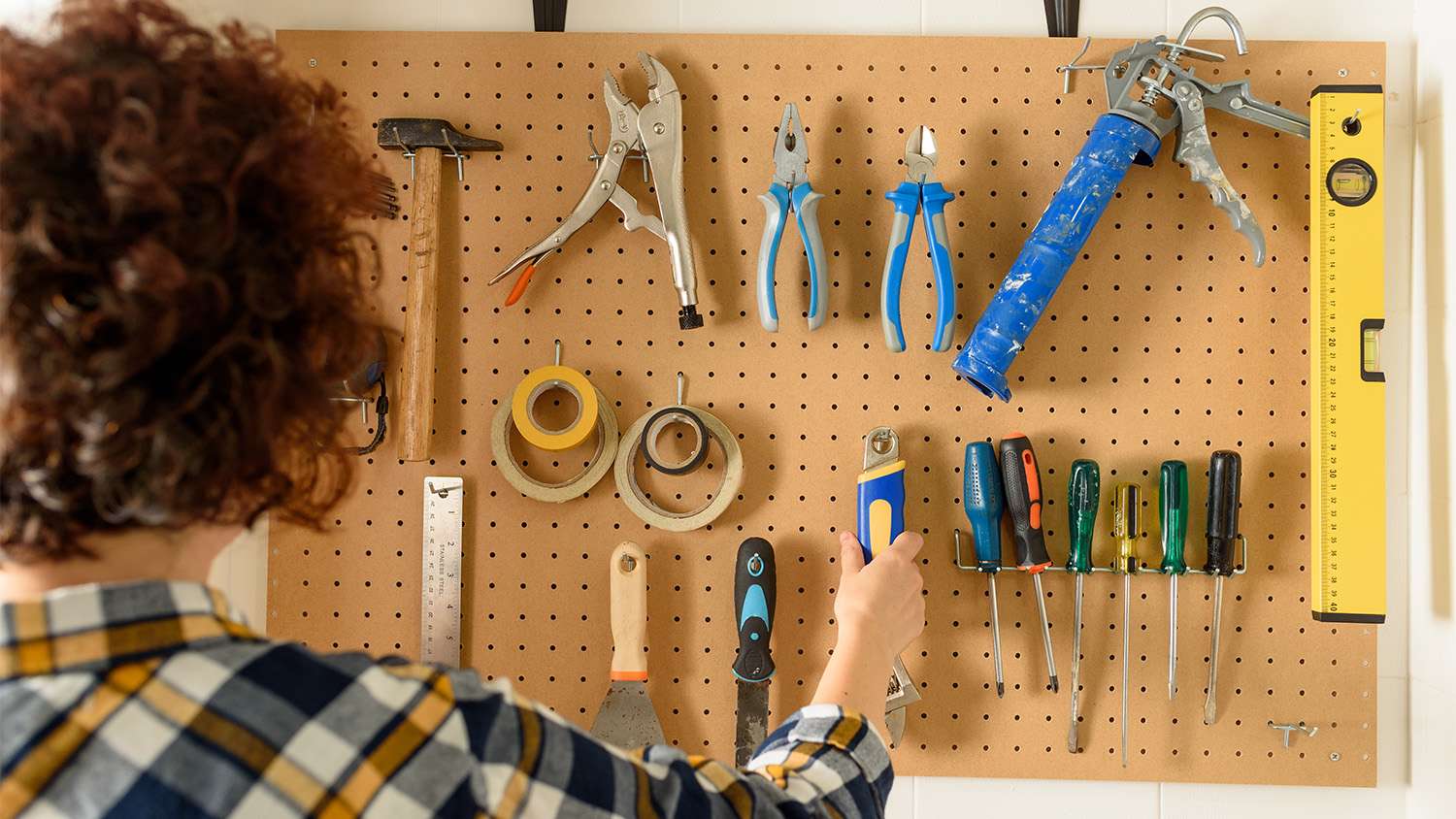 woman putting back her tools on pegboard