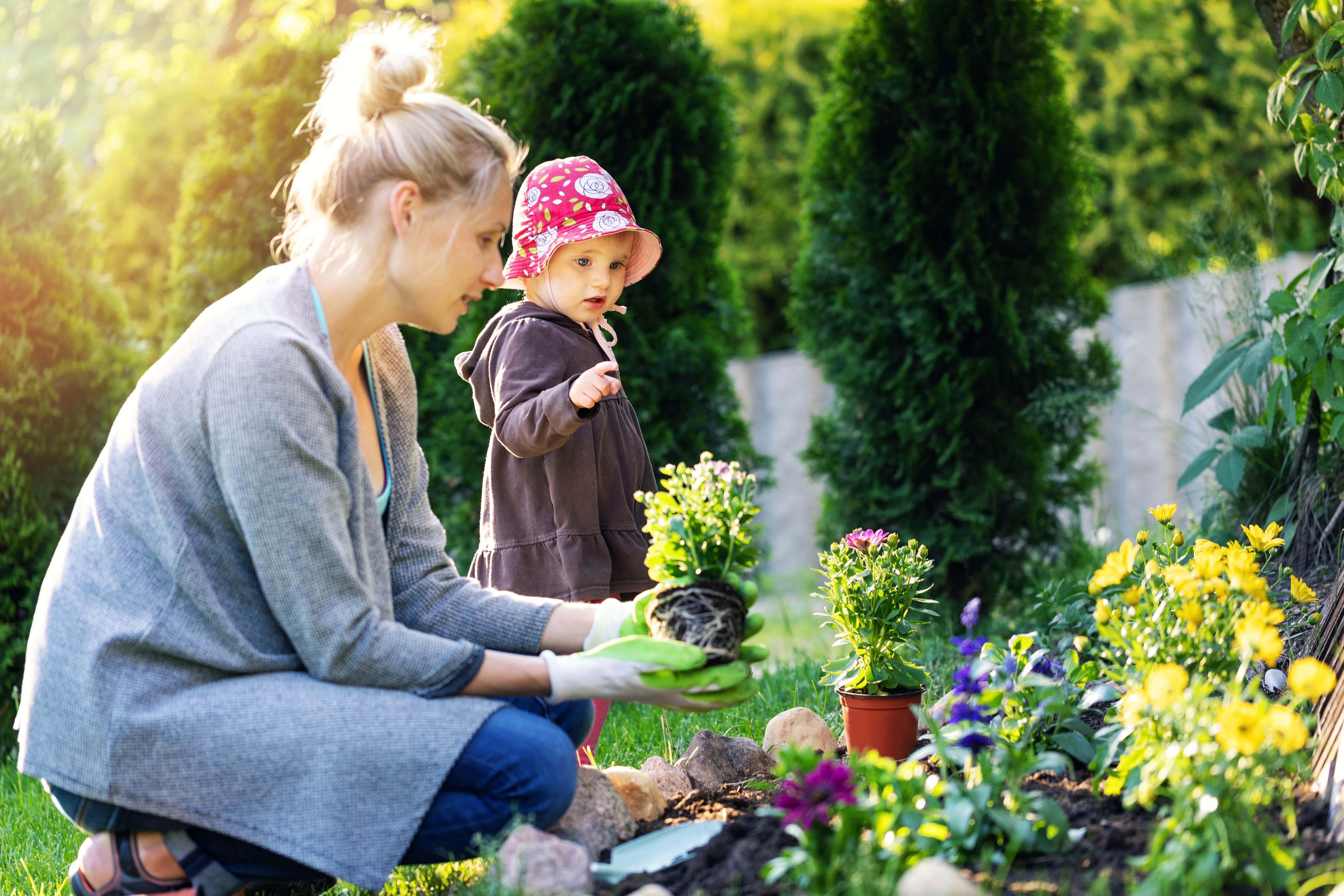 Mother and daughter planting flowers outside