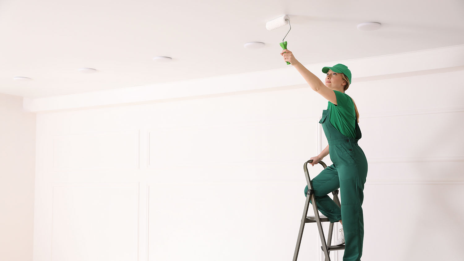 woman on ladder painting ceiling
