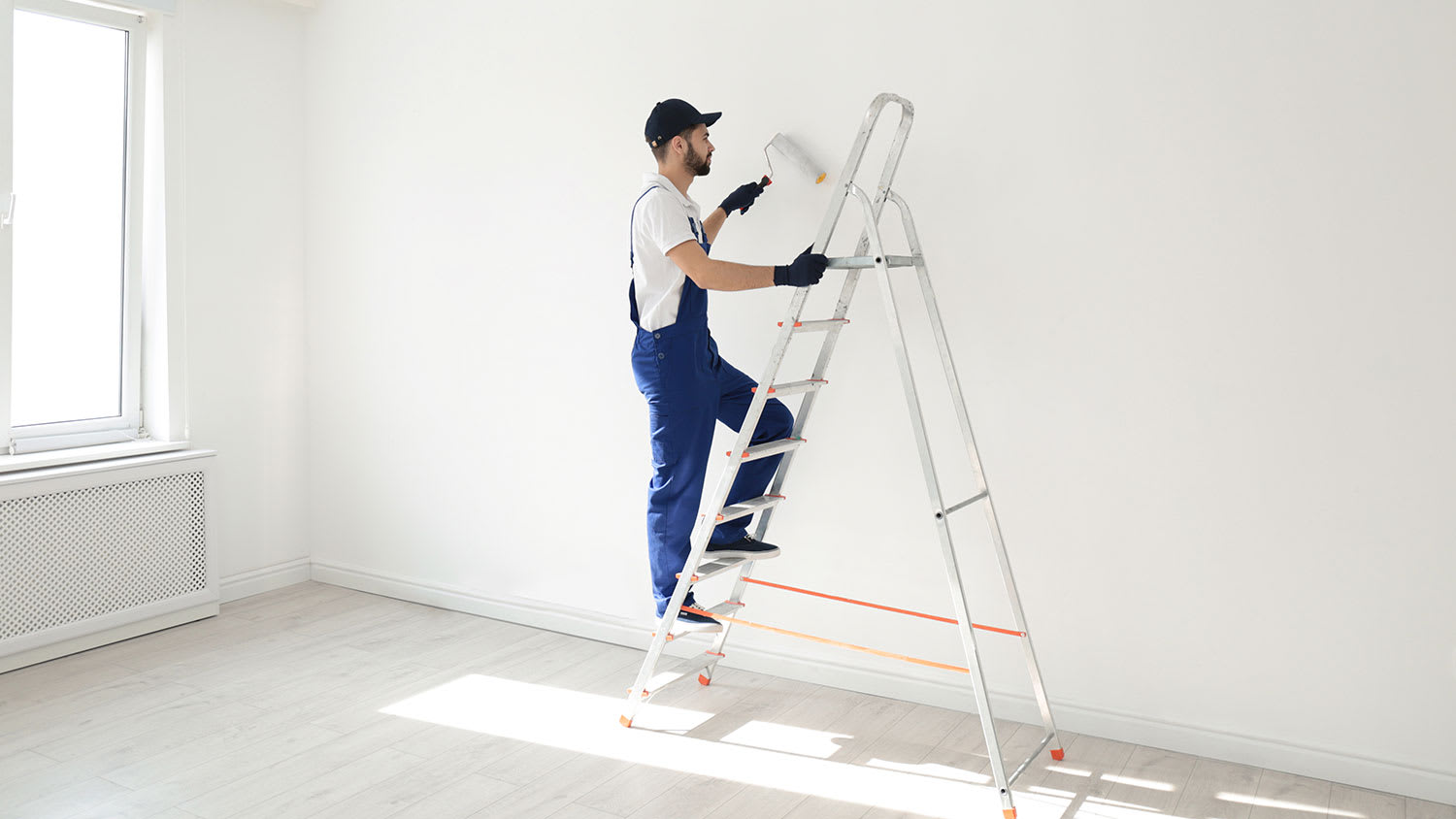 Worker on a ladder painting interior wall