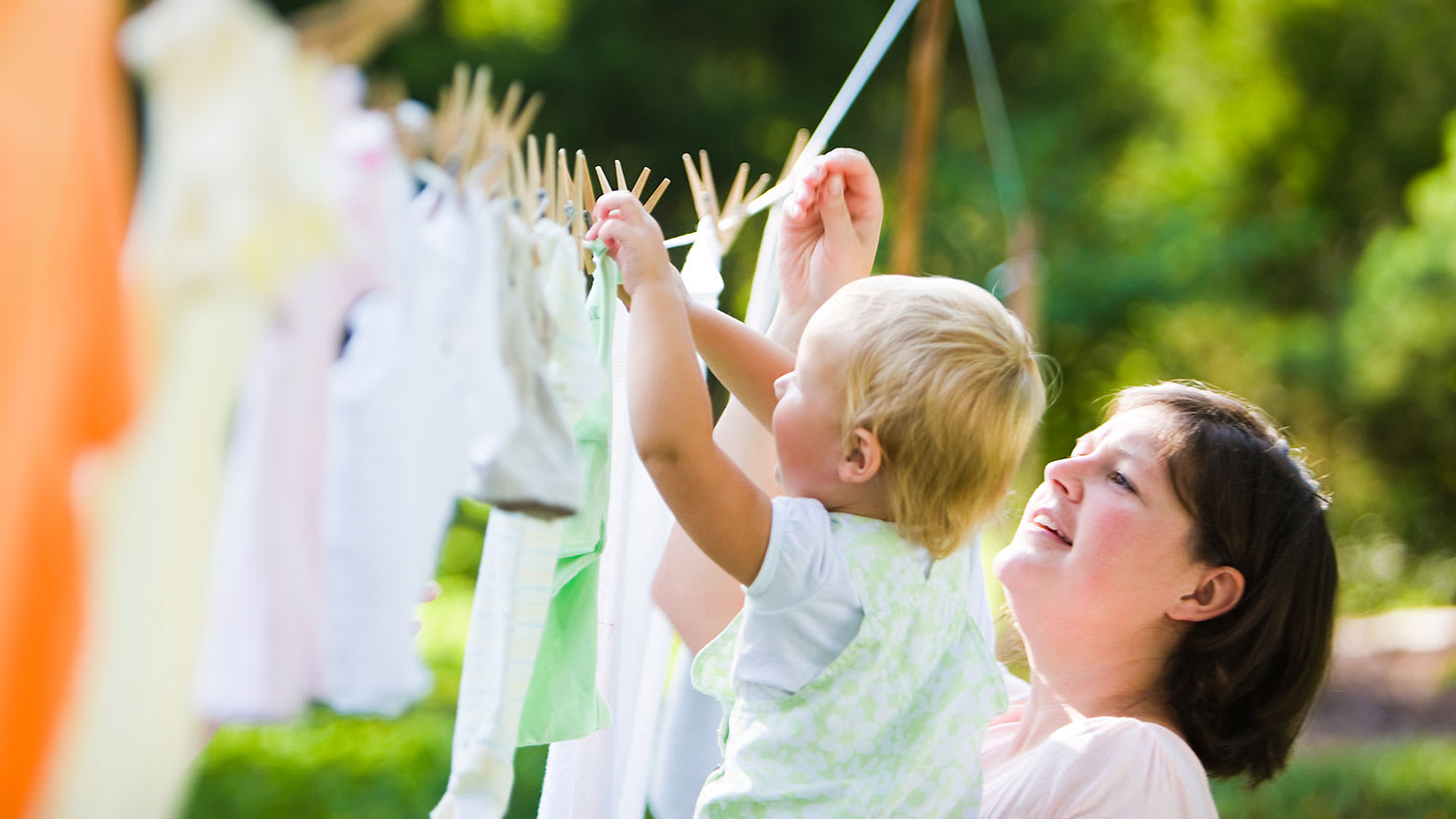Mother and child hanging clothes on clothesline