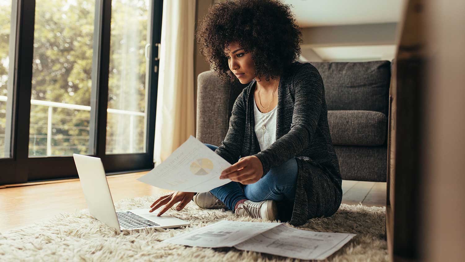 woman sitting on floor is working on her laptop