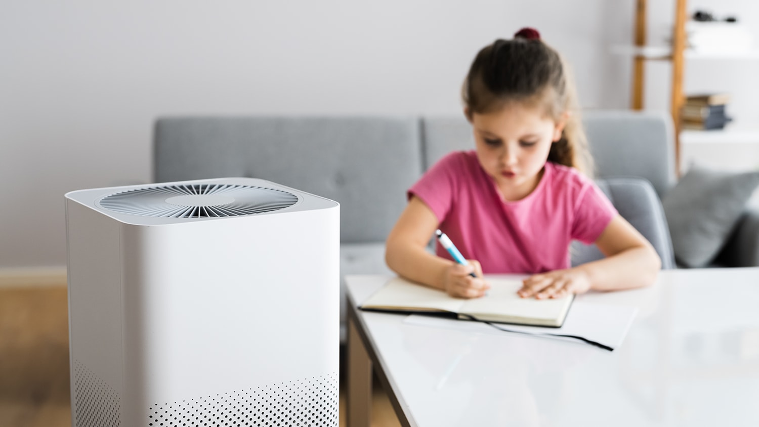 Girl sitting at table near air purifier