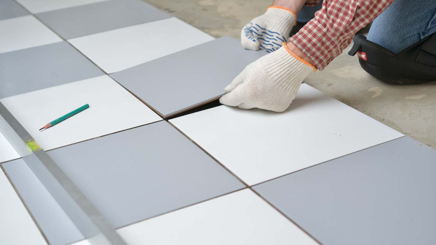 A worker wearing knee pads while installing tiles