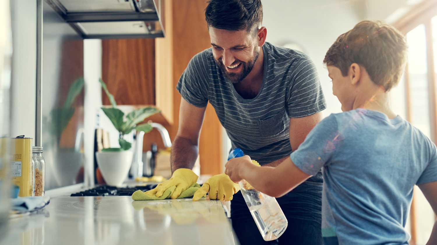 A father and his son sanitize a surface in their kitchen