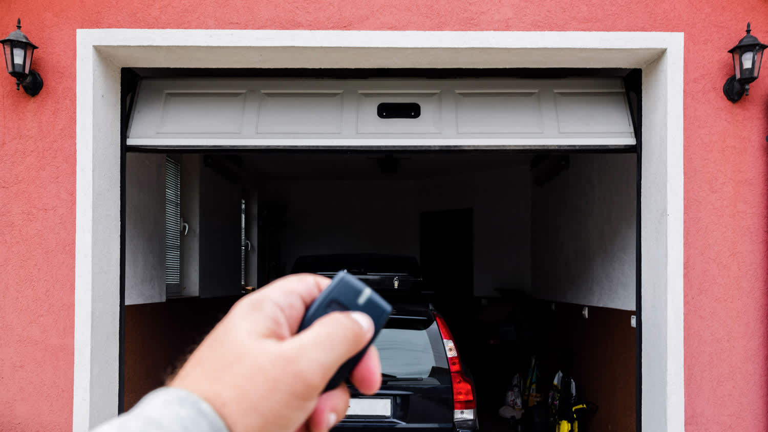 A man’s hand opening the garage door using a remote controller