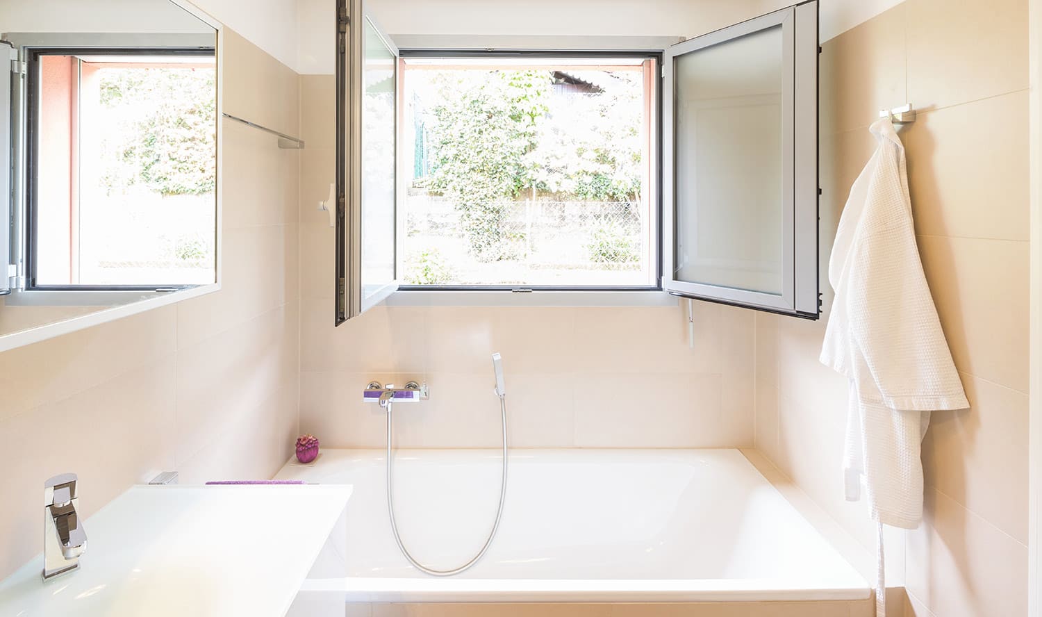 Clean bathtub with open window above