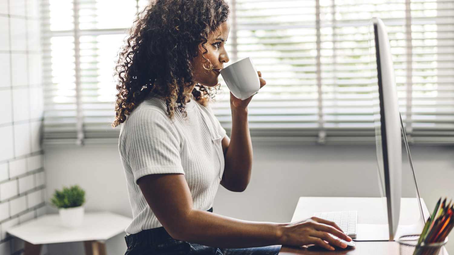 A woman sipping coffee in front of her computer