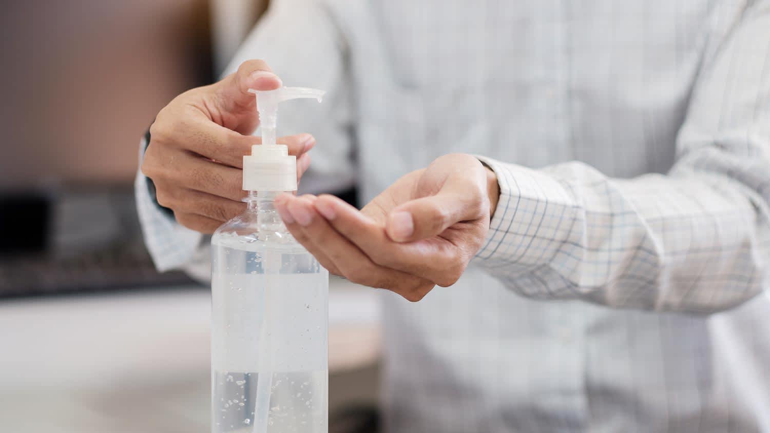 Man using sanitizer bottle dispenser