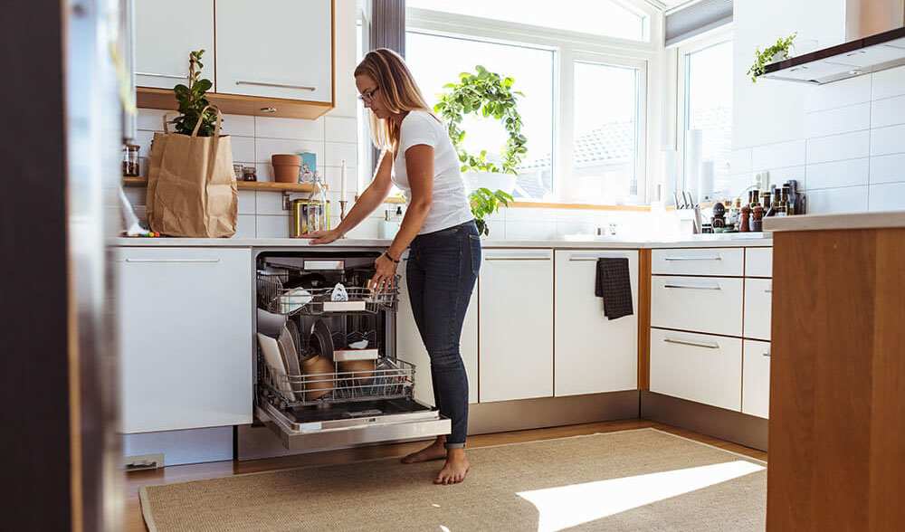 Woman unloading clean dishes from dishwasher