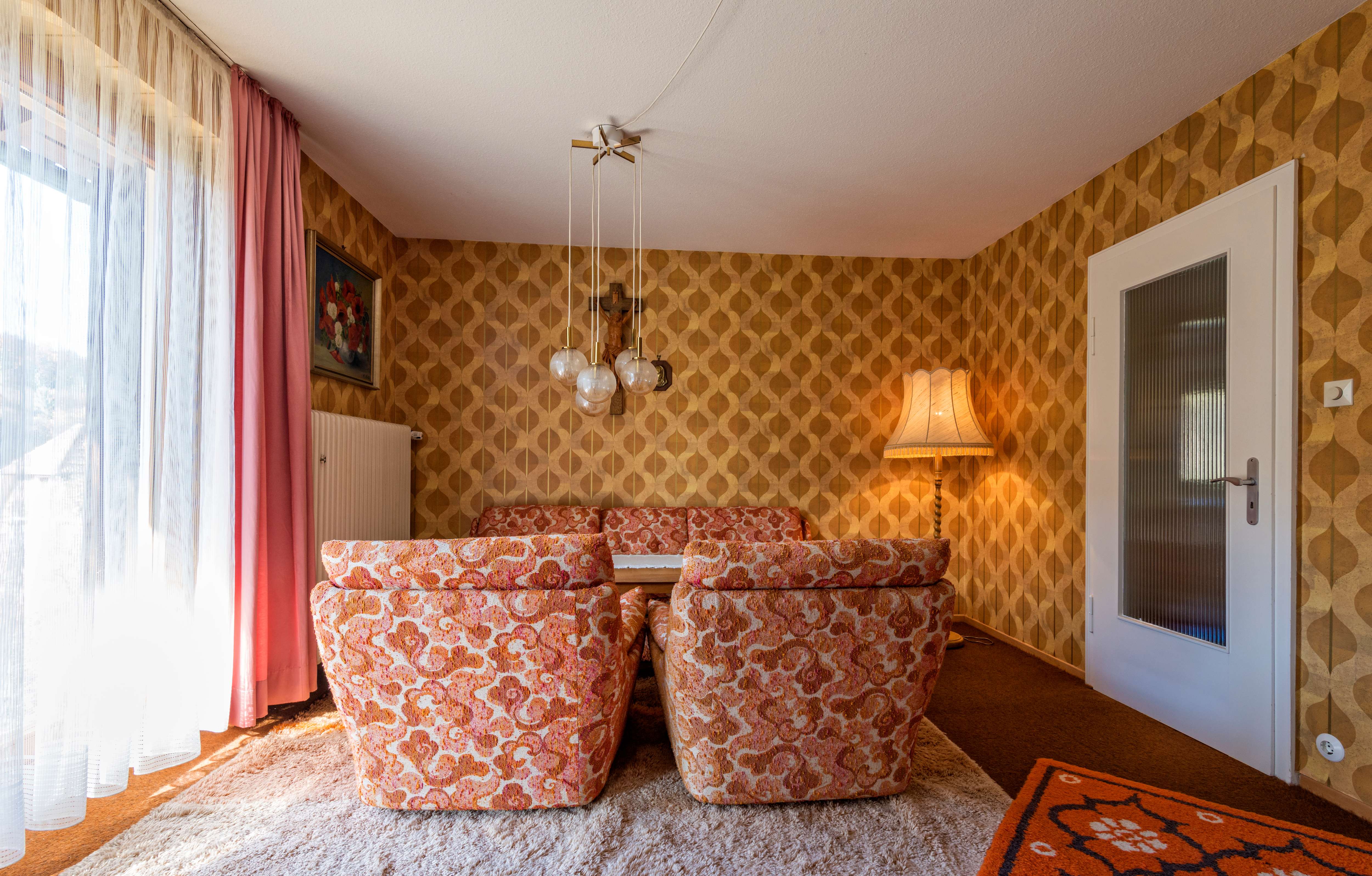 ’70s living room with orange paisley chairs and orange and brown wallpaper
