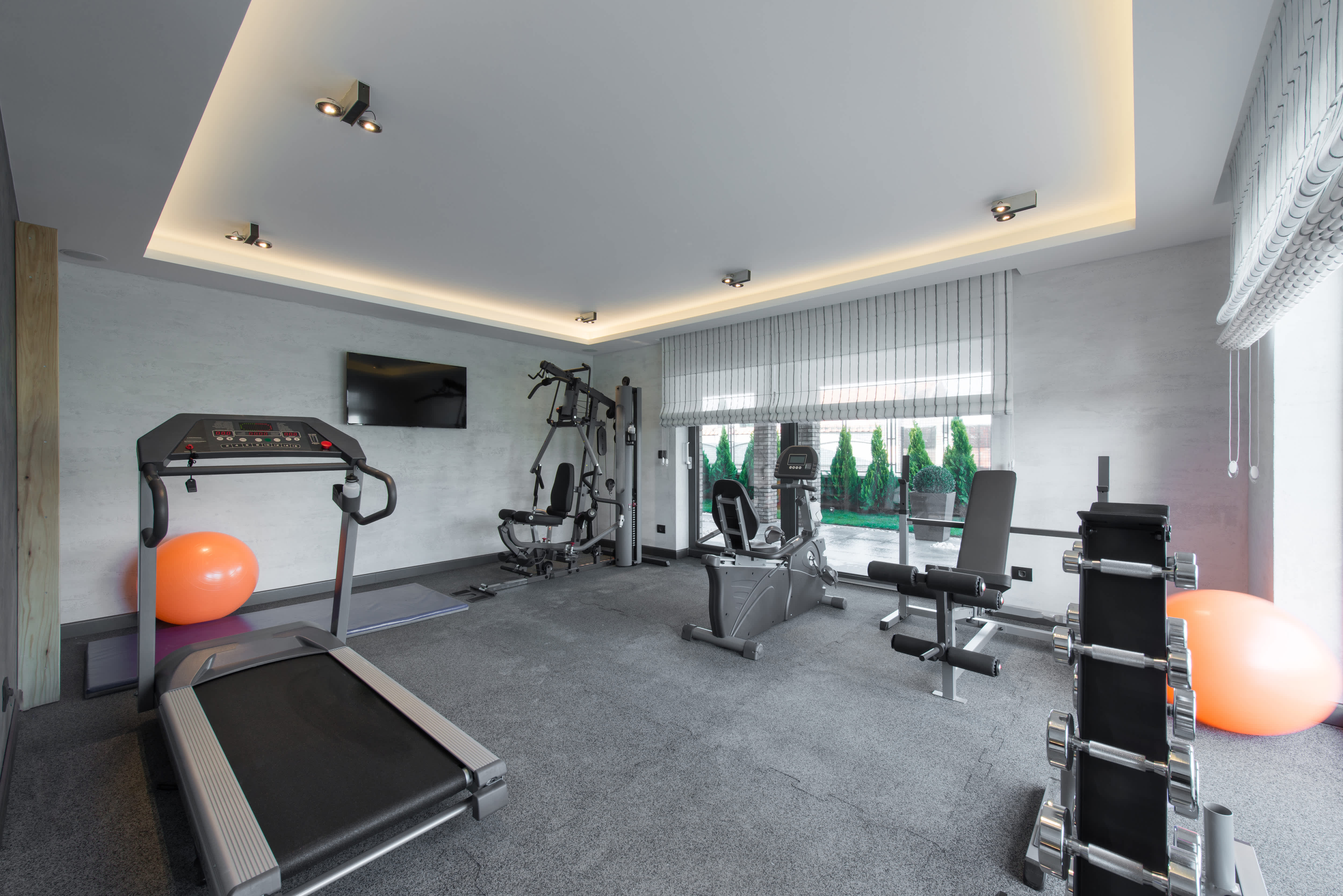 A gray home gym with a lot of workout equipment and rubber floor mats