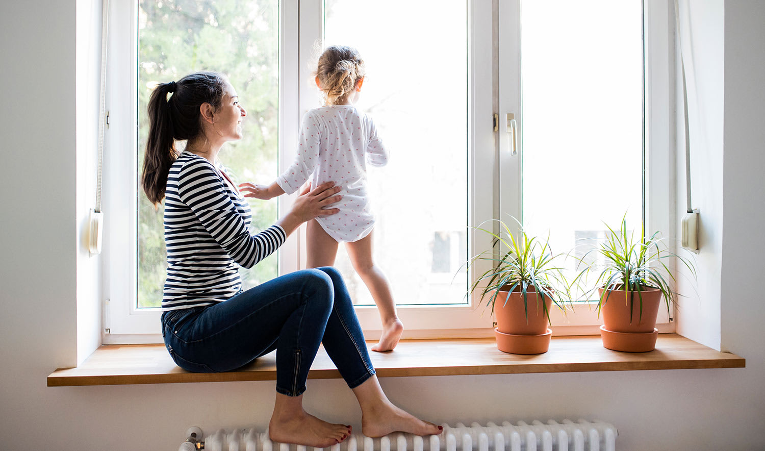 Mother with her little daughter looking out of window