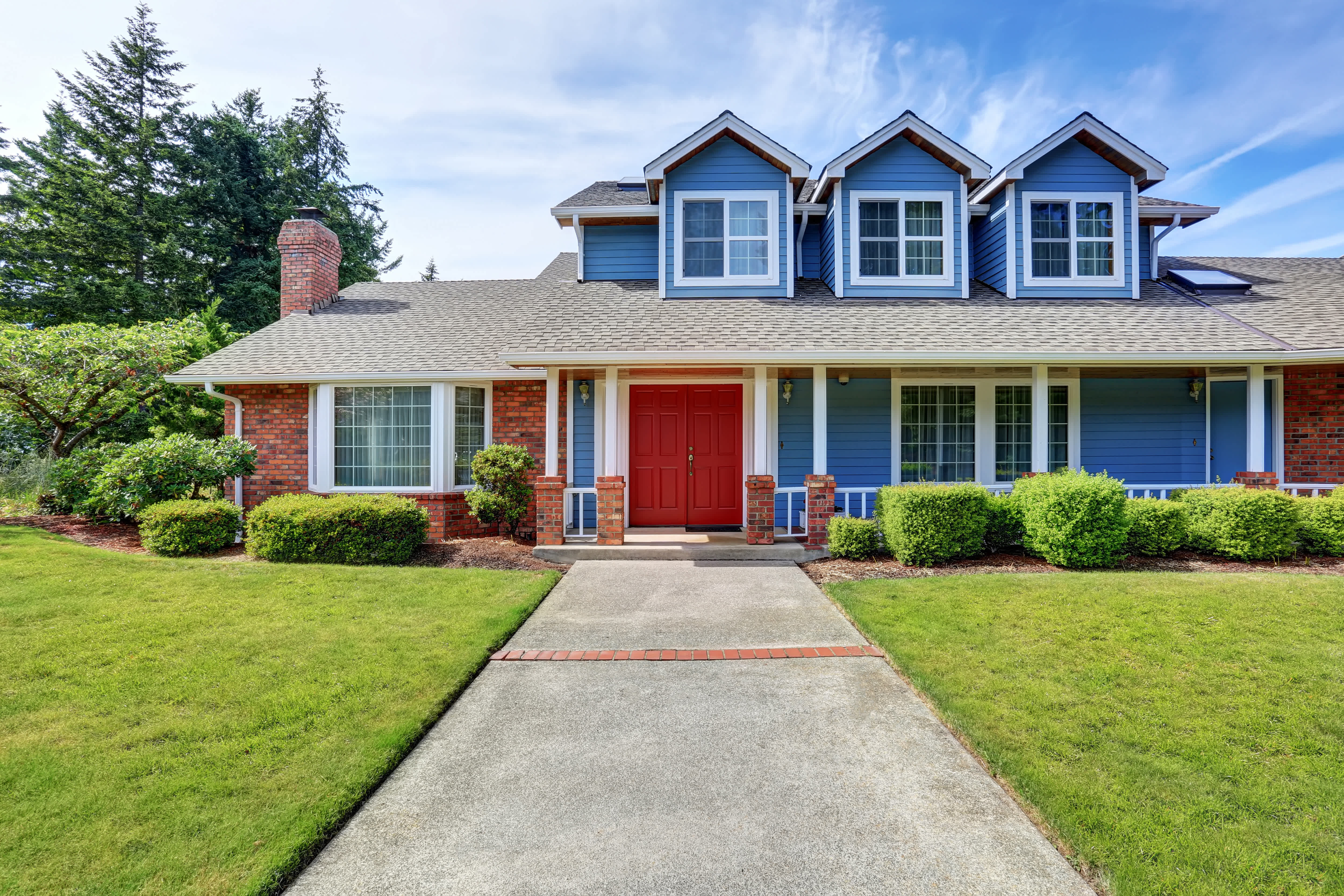 Two-story brick and blue-painted house with bold red entryway door