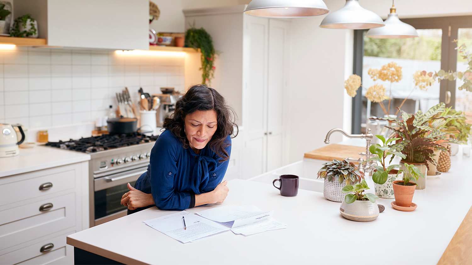 woman standing in kitchen looking at papers