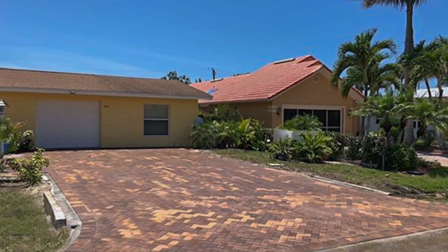Yellow large house with red brick driveway