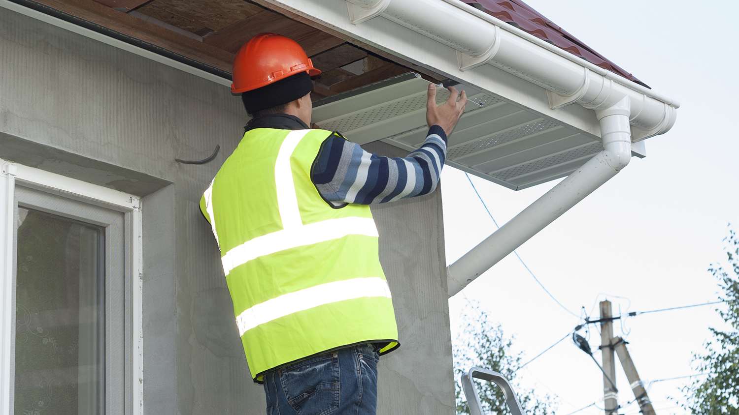 worker installing soffit on home