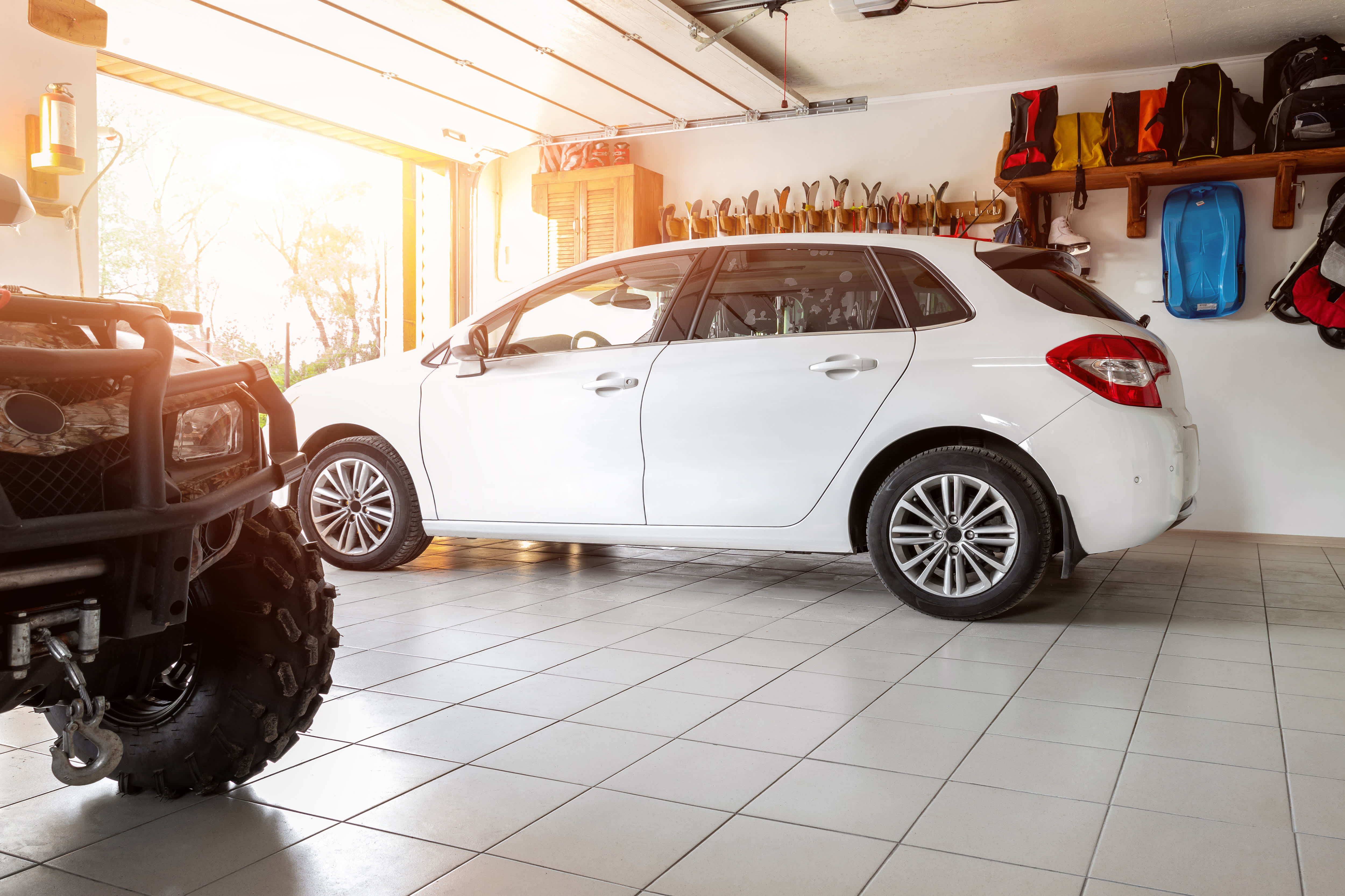 The interior of a home garage with a white SUV and an ATV parked inside