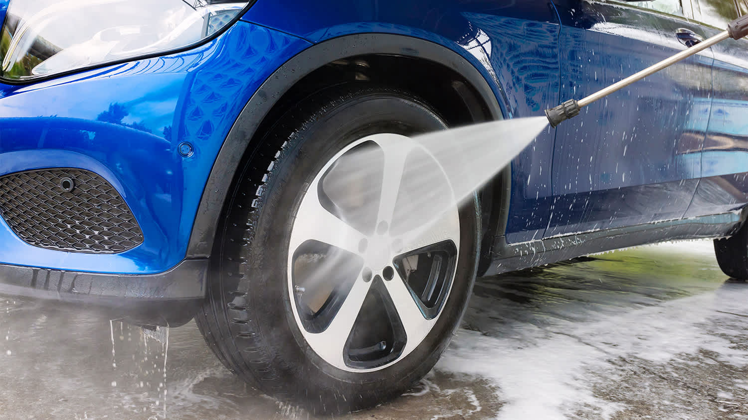 person using pressure washer to clean car tires
