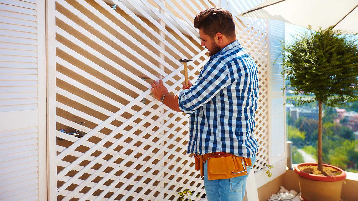 man building a wooden trellis in yard