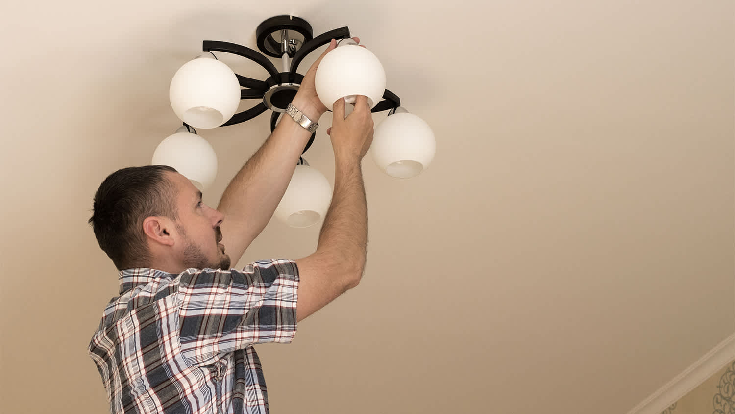 man installing bulb in light fixture