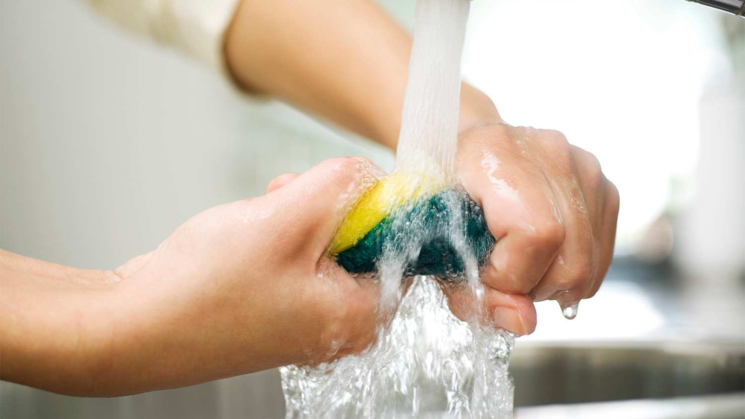 woman rinsing out sink sponge