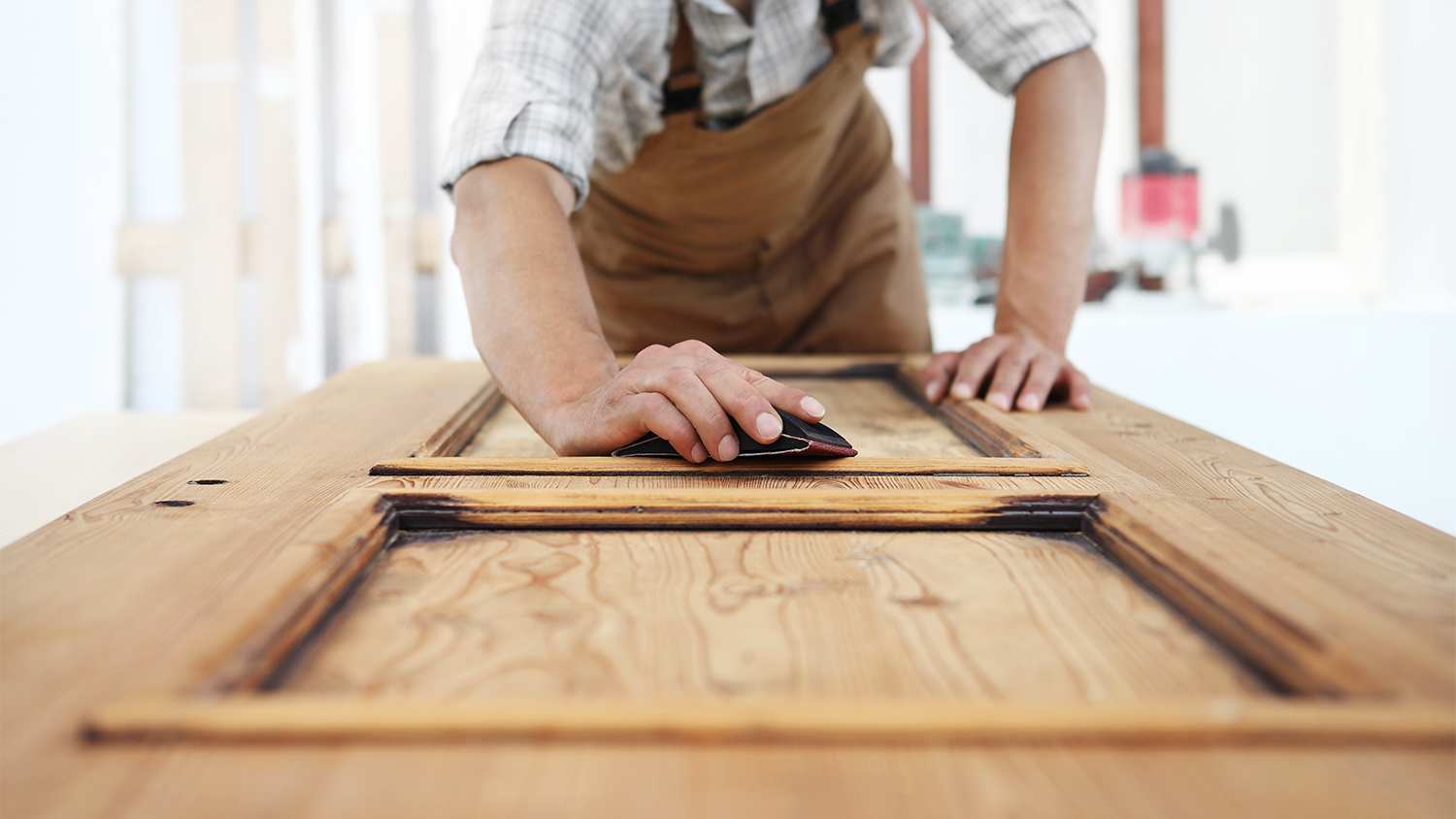 carpenter sanding down wood door