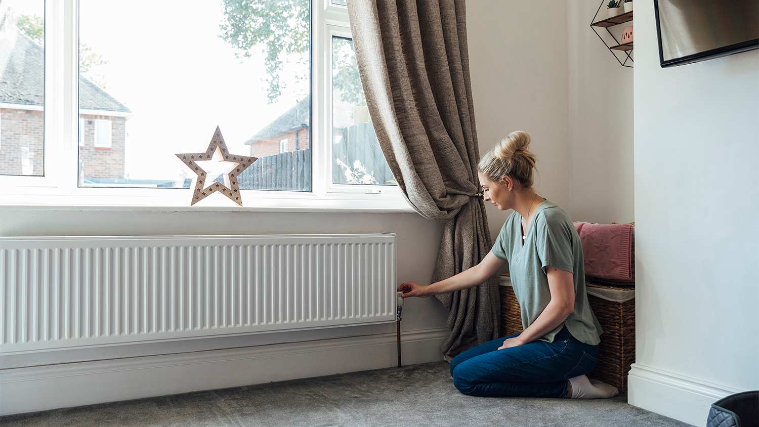 woman adjusting thermostat on radiator