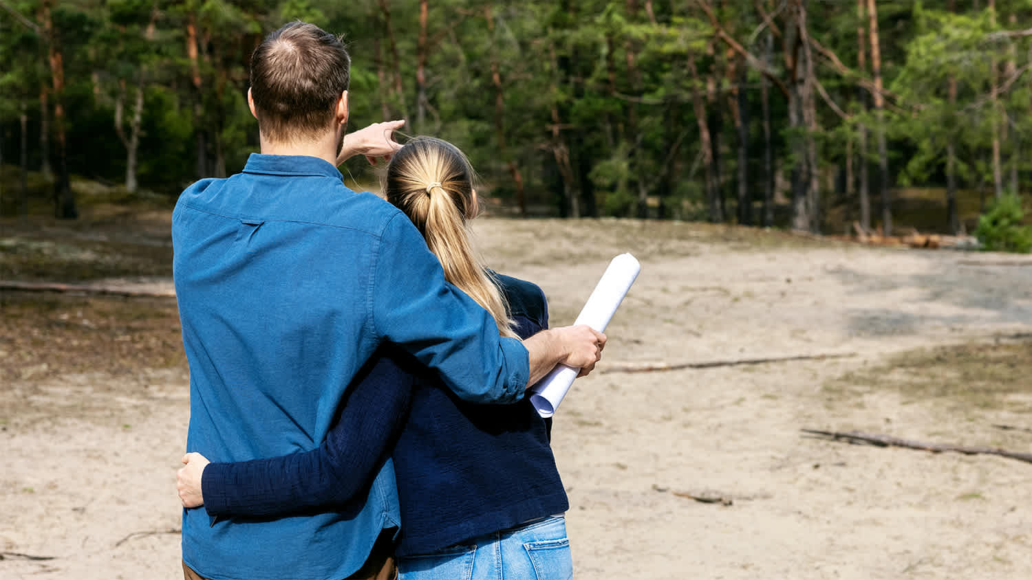 couple holding each other while looking at plot of land