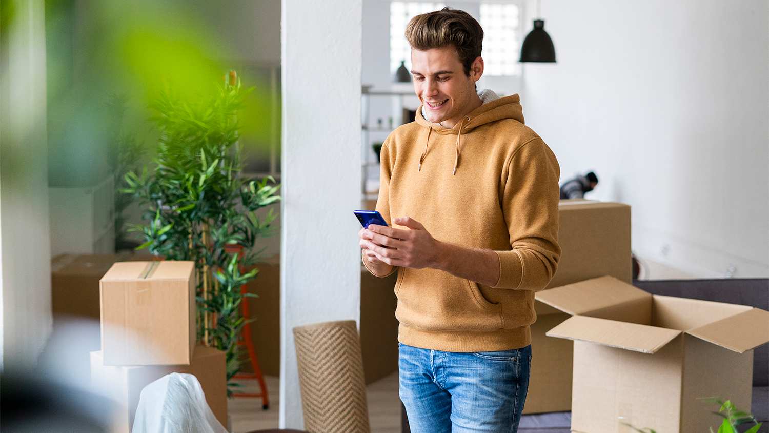 man looking at phone while moving into new apartment