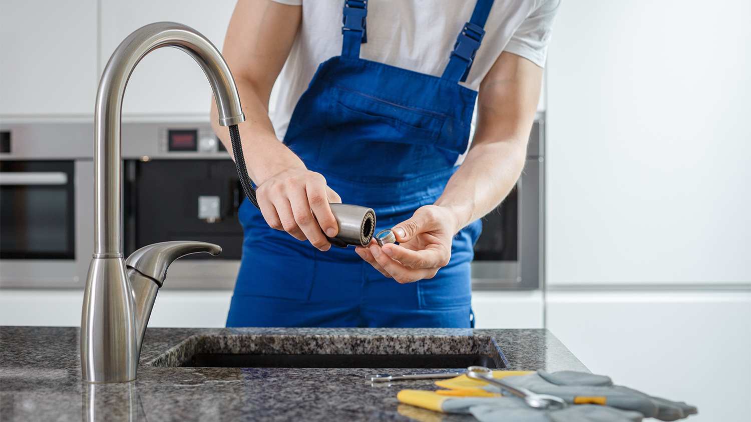 plumber fixing kitchen faucet sink