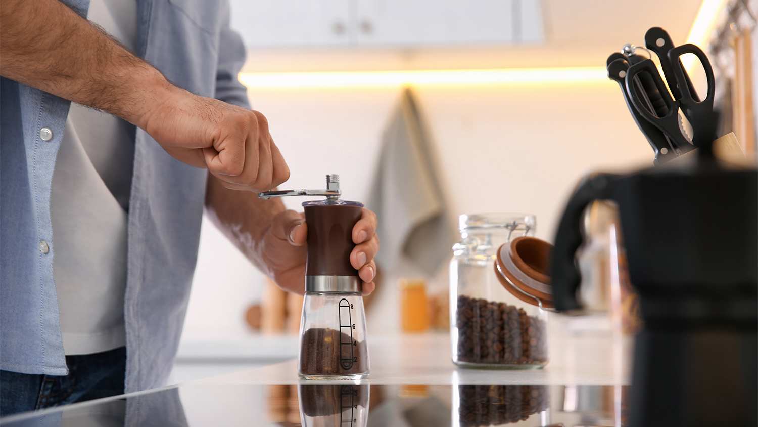 man using coffee grinder in kitchen
