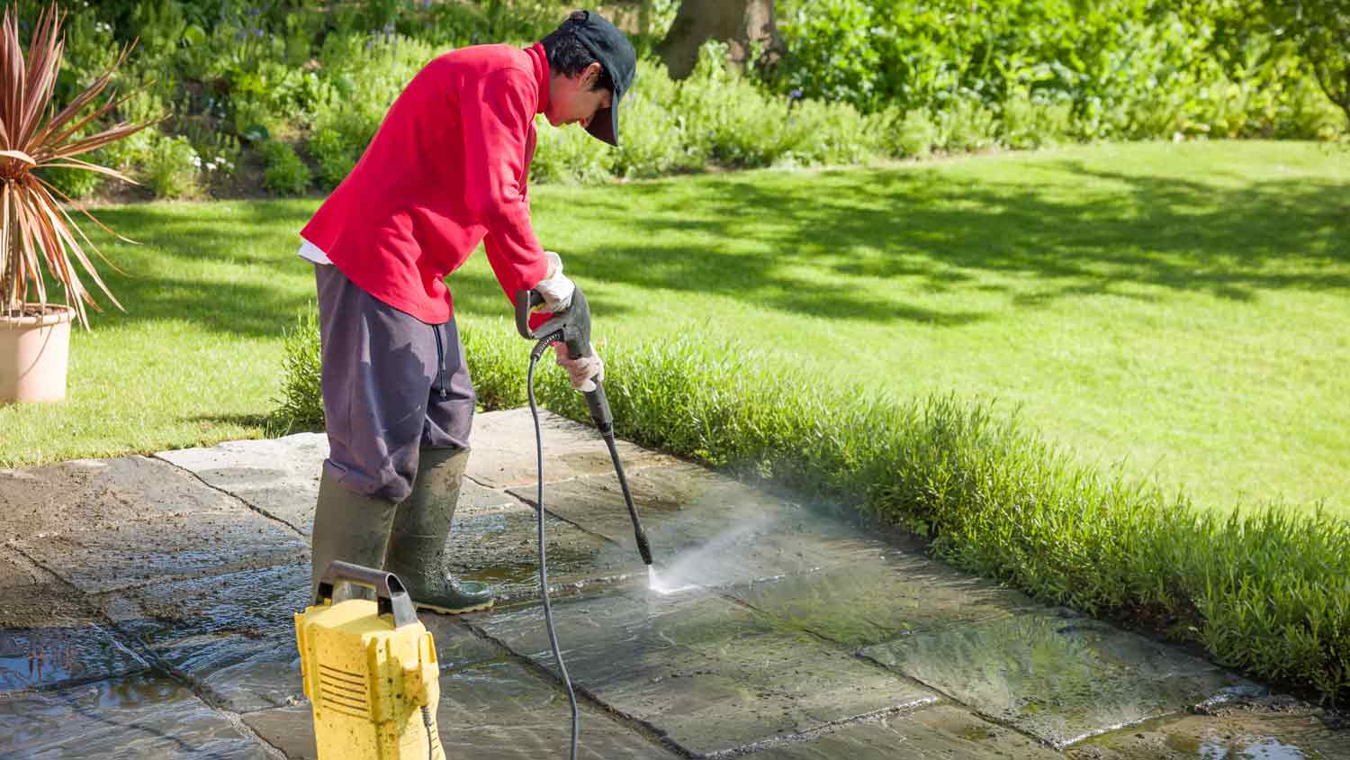 person cleaning their garden patio with pressure washer