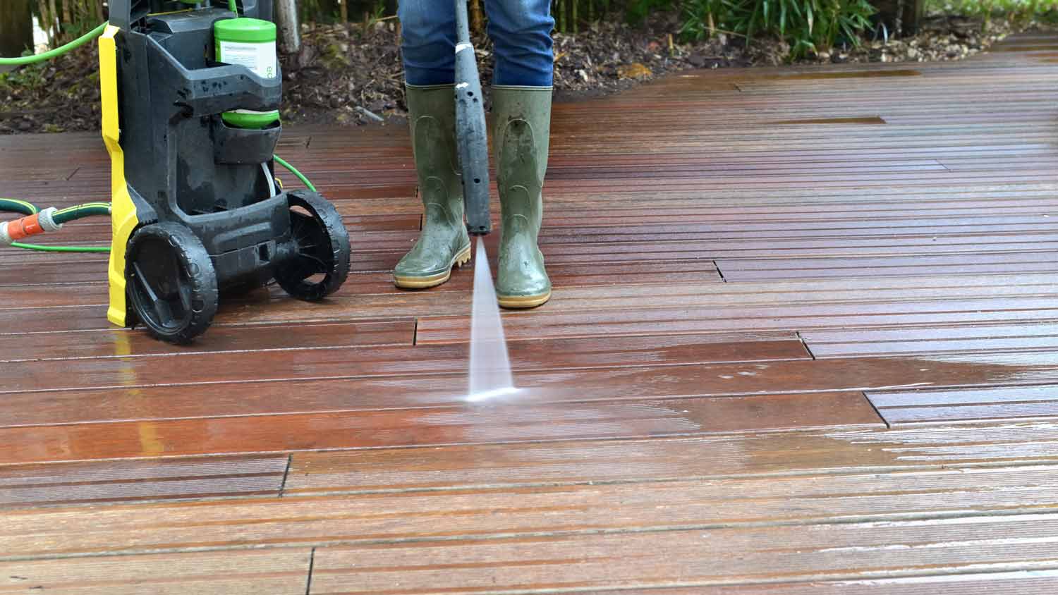 woman pressure washing wooden deck