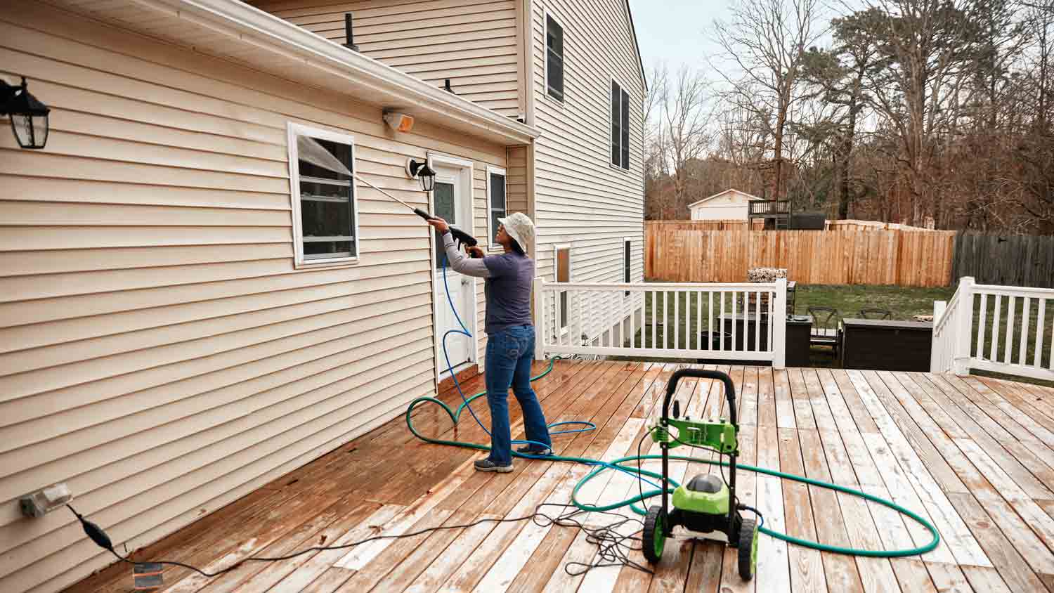 woman using pressure washer to clean wall