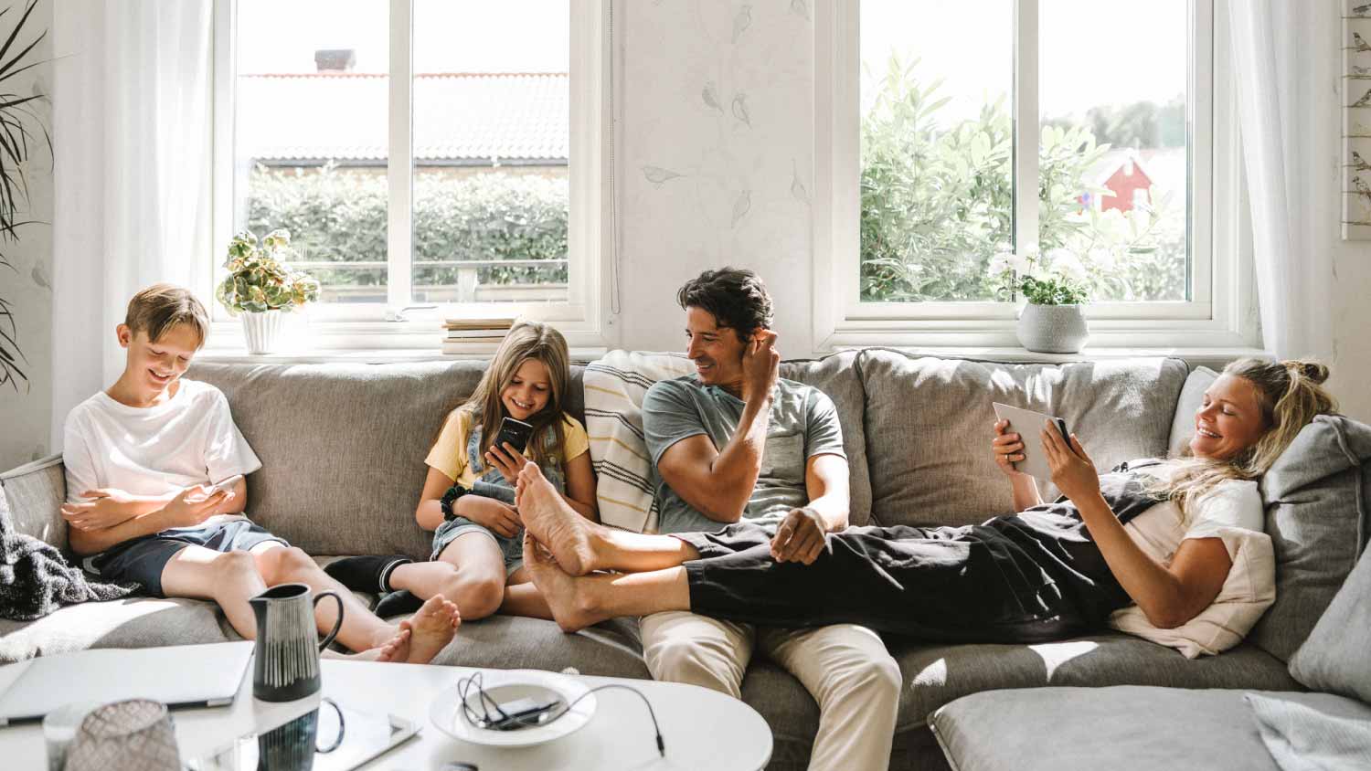A family of four relaxing on the sofa in their living room