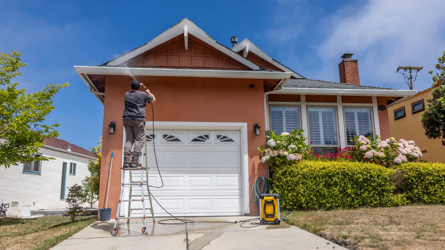 man power washing a single-family home